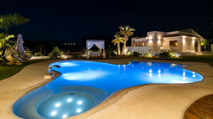 Luxury villa with illuminated pool at night