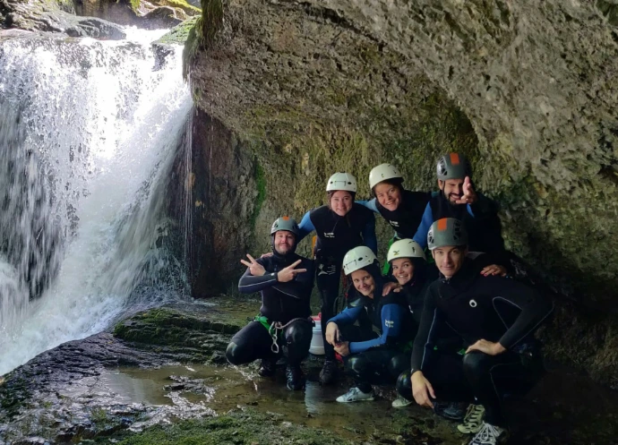 Group of friends in wetsuits by a waterfall